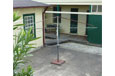 A square rusty Hill's Hoist clothes line with spokes and wires. The clothes line is attached to a stand.