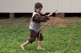 A young boy bowling a hoop with a stick.