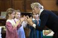 A teacher showing three girls a cat's cradle string game.