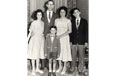 A family of two adults and three children standing in the lounge room for a photograph.