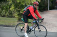 A man wearing a red helmet riding on a black bicycle.