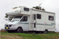 A white campervan with a sleeping area above the driver's cabin.