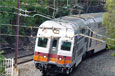 Two carriages of a silver electric train on tracks rounding a bend.