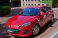 A small red hatchback car with chrome wheels.