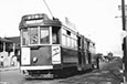 This old tram carries people from one place to another; it runs on rails and is powered by electricity.