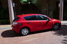 A small red hatchback car with chrome wheels