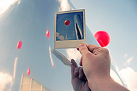 Hand holding photo of a balloon floating in the sky