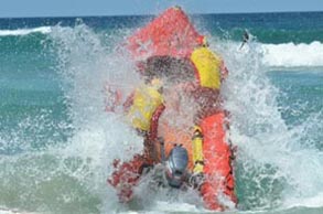 inflatable surfboat being driven through the surf by lifesavers