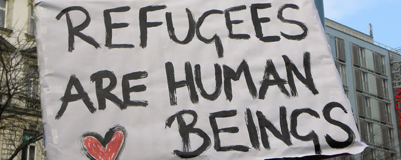 Hand painted sign that says "refugees are human beings".