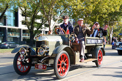 A vintage car with three old men, two are waving and one is wearing lots of medals. A vintage car with three old men, two are waving and one is wearing lots of medals.