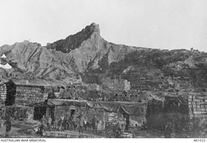 Several men standing in front of boxes many groups of stacked boxes; in the background is the Sphinx.