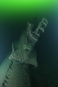 An encrusted submarine lying in green water An encrusted submarine lying in green water