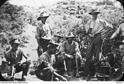 A black and white photograph of 8 men, some sitting, some standing, some eating, some drinking. A black and white photograph of 8 men, some sitting, some standing, some eating, some drinking.