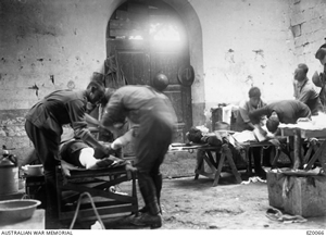 Inside a building men are leaning over and attending to two men on make-shift beds