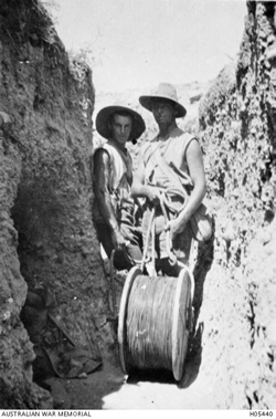 Two men stand in a cutting with a cable drum Two men stand in a cutting with a cable drum