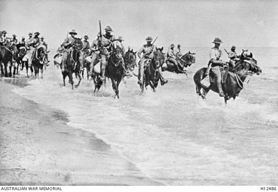 Men in uniform riding horses through shallow water Men in uniform riding horses through shallow water