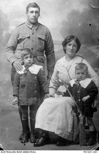 A family portrait circa 1915 of a uniformed man standing, a seated woman and two children.