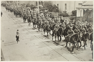 Row of men on horseback riding down a street Row of men on horseback riding down a street